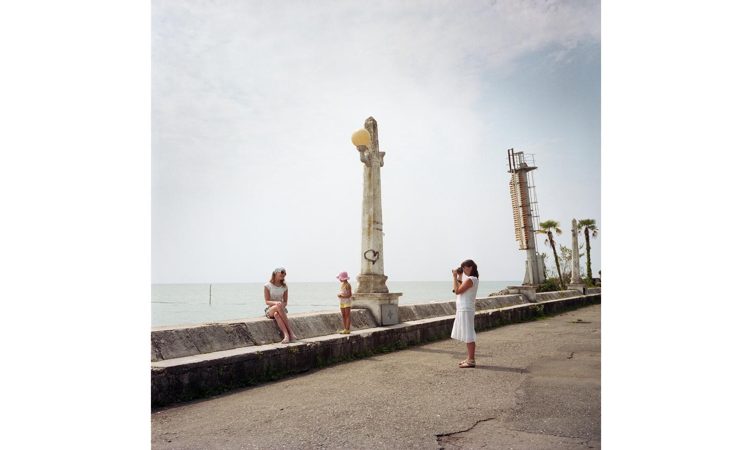 Tourists take photos in Sukhum(i) along the seaside.