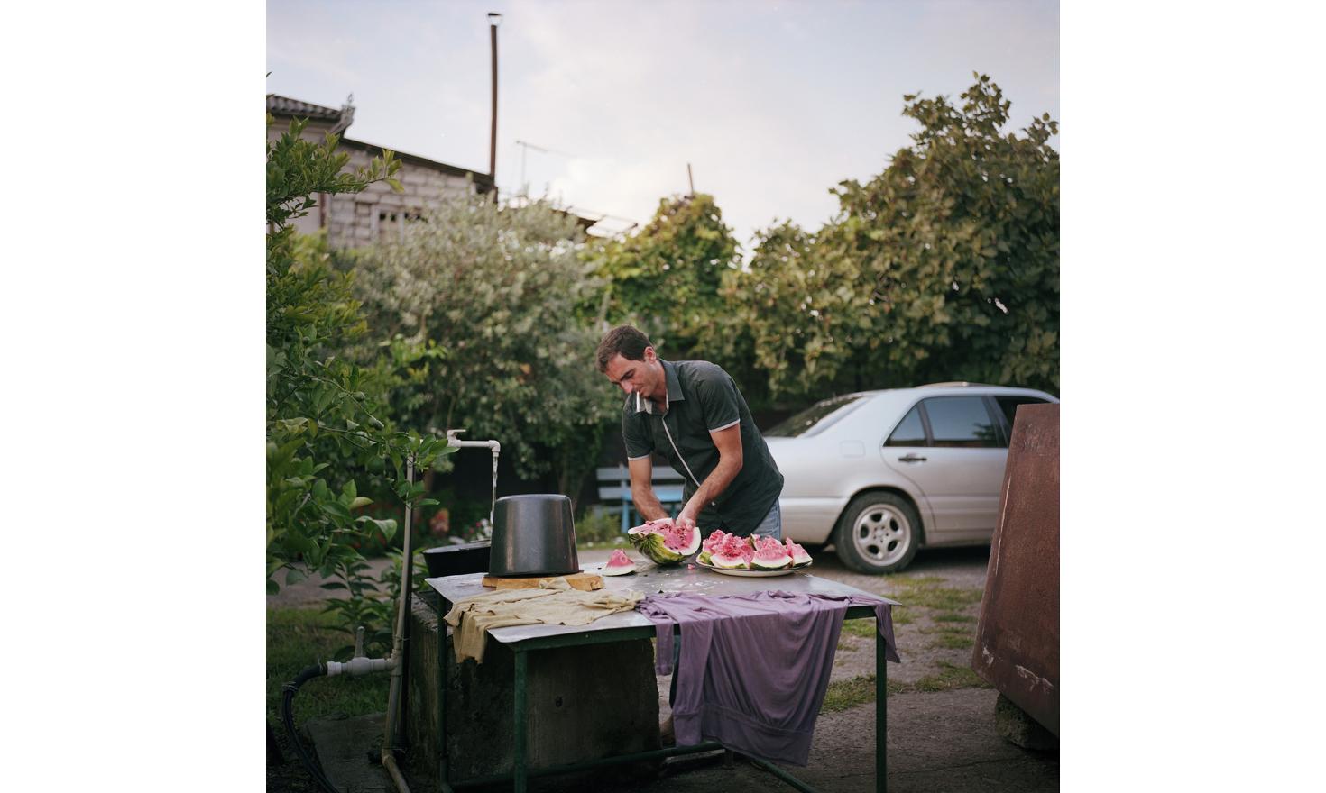 Samvel, an Armenian who lives in Sukhumi, cuts a watermelon in his garden where he grows mandarins.