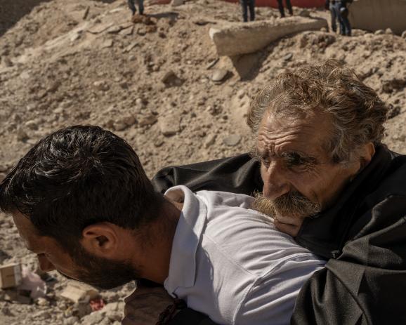 Un vieillard est porté sur le dos, alors qu'il faut que les gens traversent à pied le trou laissé par une frappe israélienne, qui coupe en deux la route entre le Liban et la Syrie, à Masnaa, poste frontière entre le Liban et la Syrie, bombardé vendredi le